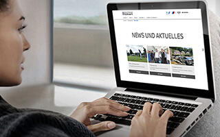 Frau surft auf einem Laptop auf einer BMW-Webseite im Bereich "News und Aktuelles".
