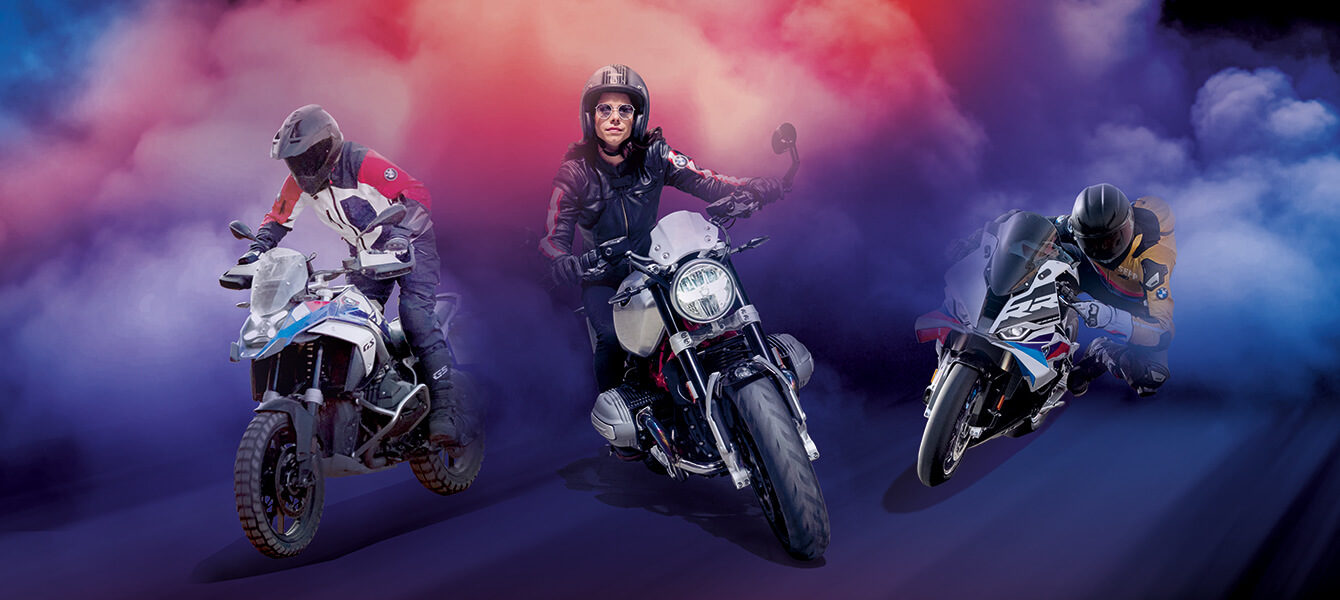 Drei BMW Motorradfahrer auf GS, Heritage und Sport Modellen in dynamischer Inszenierung vor farbigem Nebelhintergrund.