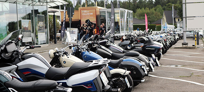 Reihe hochwertiger BMW Motorräder vor einem Showroom, bereit für eine Testfahrt zu BMW Motorrad on Tour.