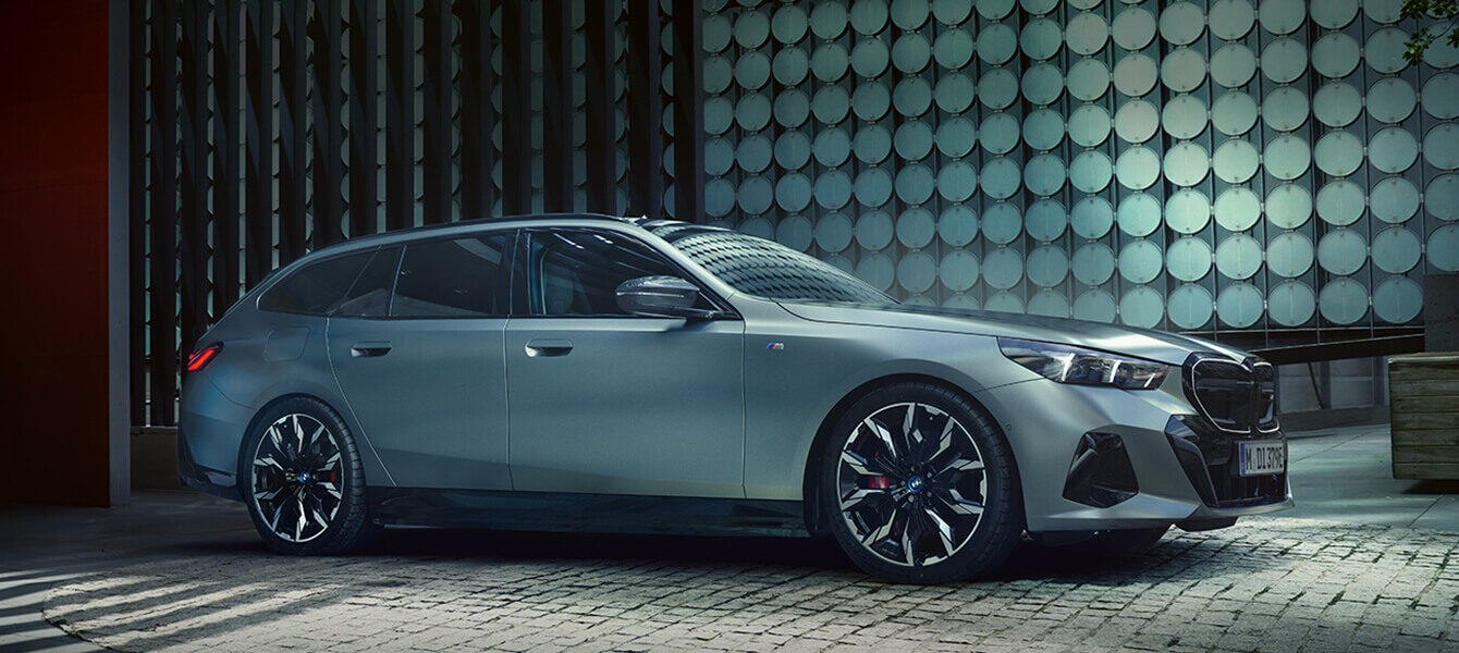 BMW i5 M60 Touring in Frozen Pure Grey metallic – sportlicher Elektrokombi mit M Performance Paket in urbaner Nachtkulisse.