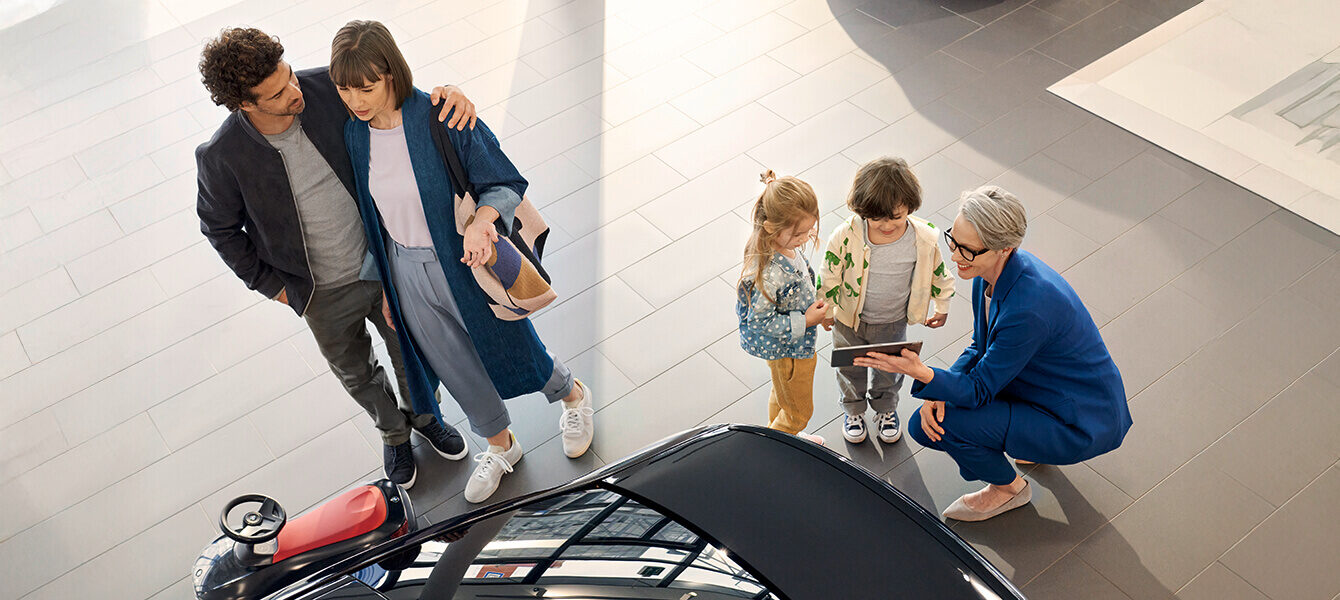 Familie mit zwei Kindern erhält Beratung zu einem Elektroauto in einem Autohaus.