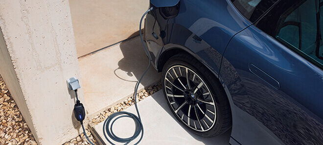 Elektroauto wird an einer privaten Wallbox an einem Wohngebäude geladen.