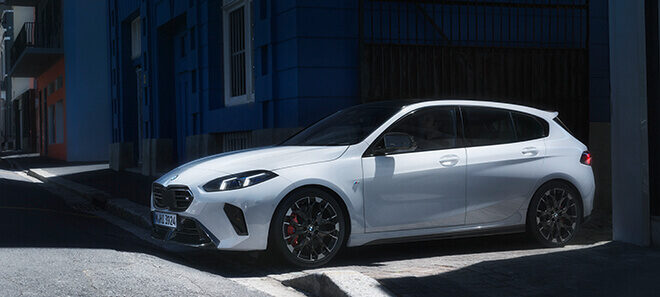 BMW M135i in Weiß vor urbaner Architektur in Seitenansicht.