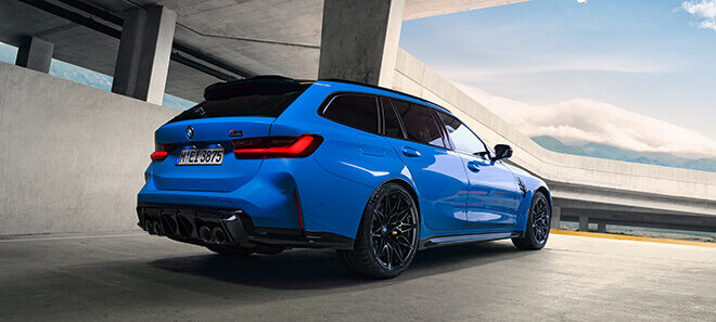 BMW M3 Competition Touring in Blau vor moderner Betonarchitektur.