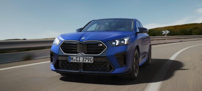 BMW X2 M35i in Blau auf kurviger Landstraße während der Fahrt.