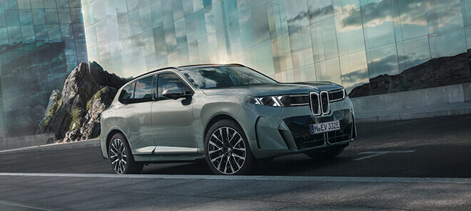 BMW X5 vor moderner Glasfassade in urbaner Umgebung.