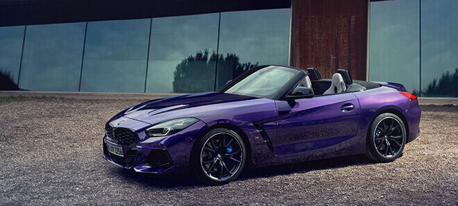 BMW Z4 M40i Roadster in Violett vor moderner Architektur.