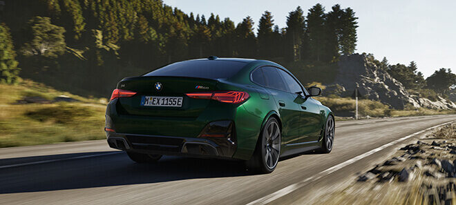 BMW i4 M60 in Grün auf Landstraße in dynamischer Heckansicht.