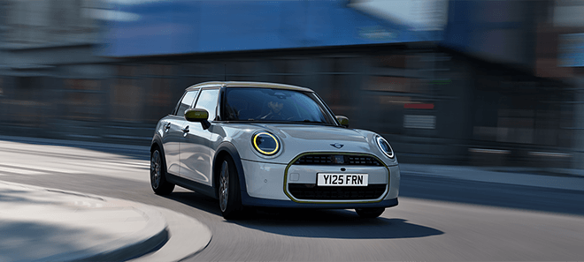MINI Cooper 5-Türer Paul Smith Edition in Weiß mit grünen Designakzenten bei dynamischer Fahrt durch die Stadt