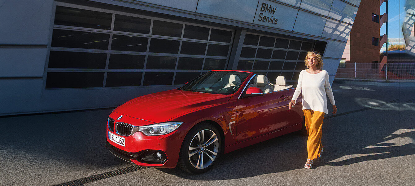 Rotes BMW Cabrio mit Kundin vor dem BMW Service bei Autohaus Kühnert